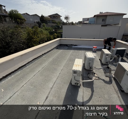אדם עובד על גג עם ציוד איטום ומזגנים